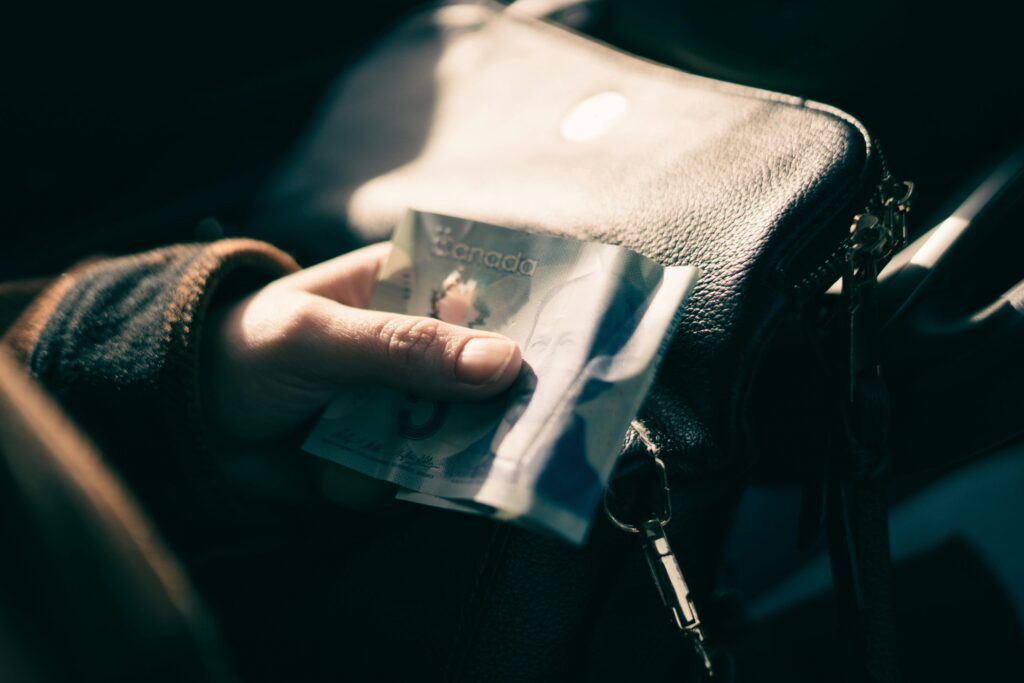 Person pulling a Canadian banknote from a purse, representing accessing quick funds through a payday loan in Canada