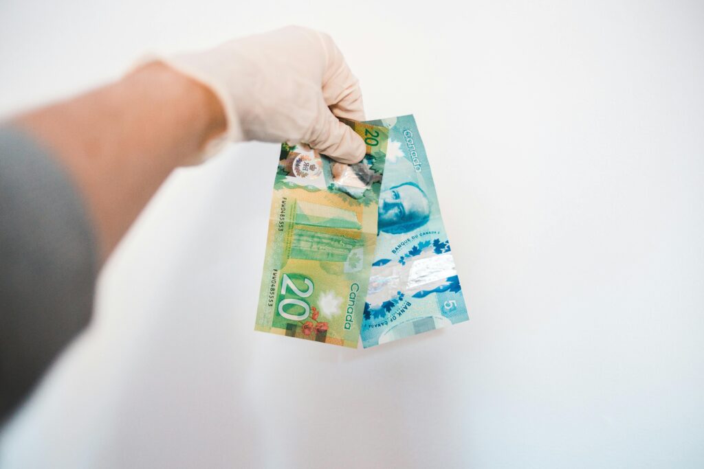Hand holding Canadian $20 and $5 polymer banknotes representing fast payday loan cash in Canada