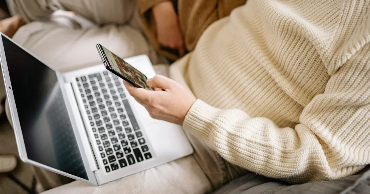 Person applying for a $200 no credit check loan in Canada on a phone and laptop