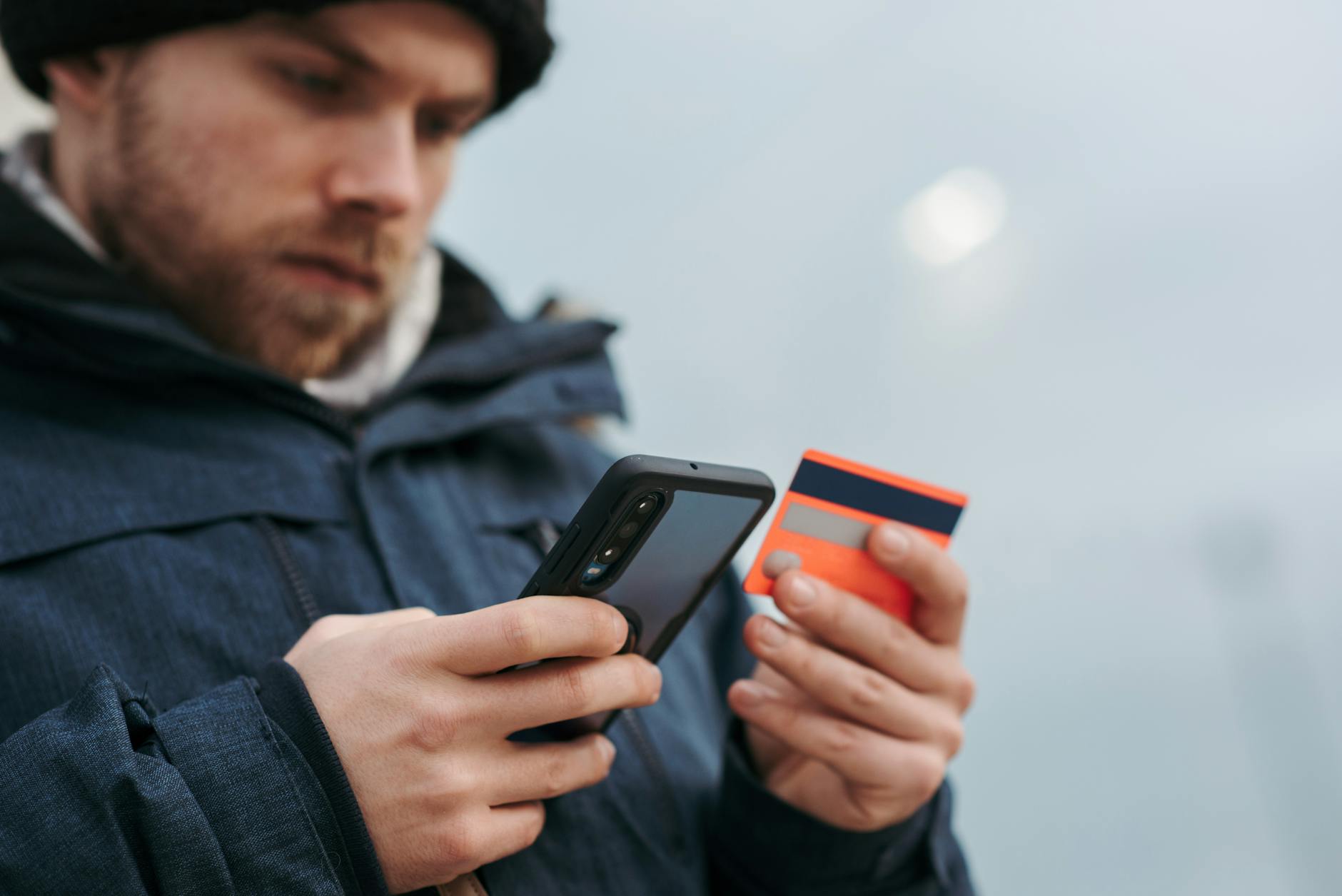 Man entering credit card details on mobile phone for online loan Canada