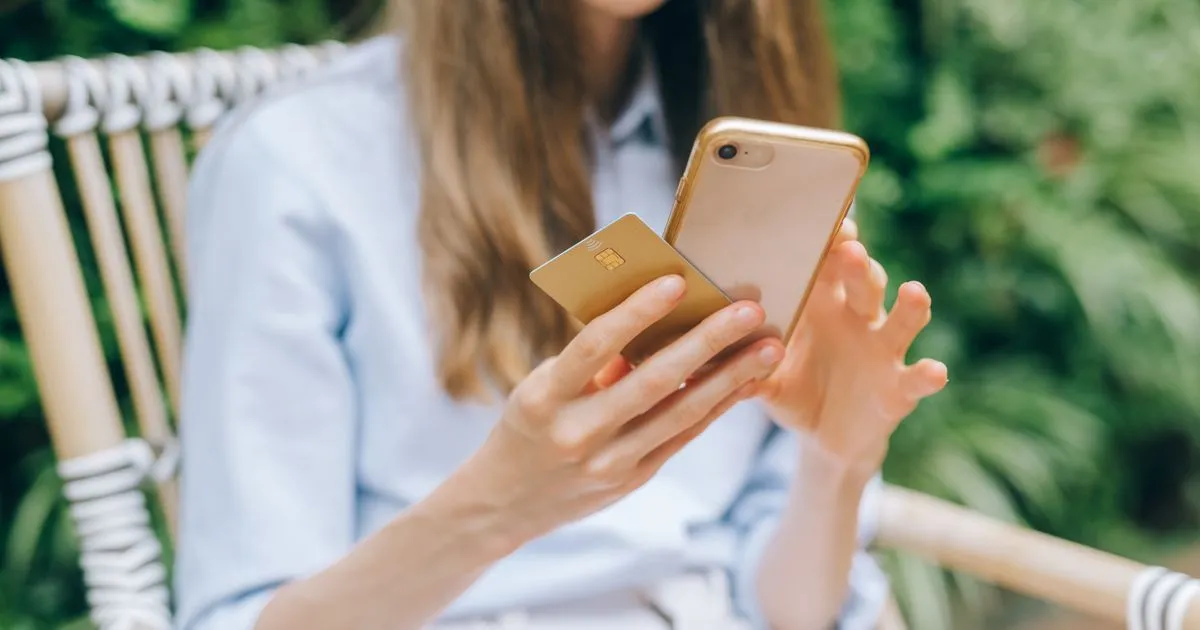 Instant loan apps Canada user checking her phone with a credit card outdoors