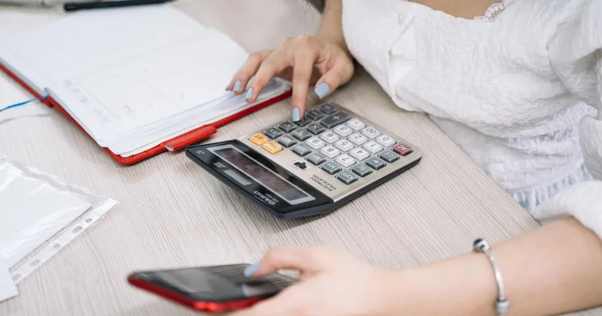 Adding up what instant loan apps cost with a calculator and notebook