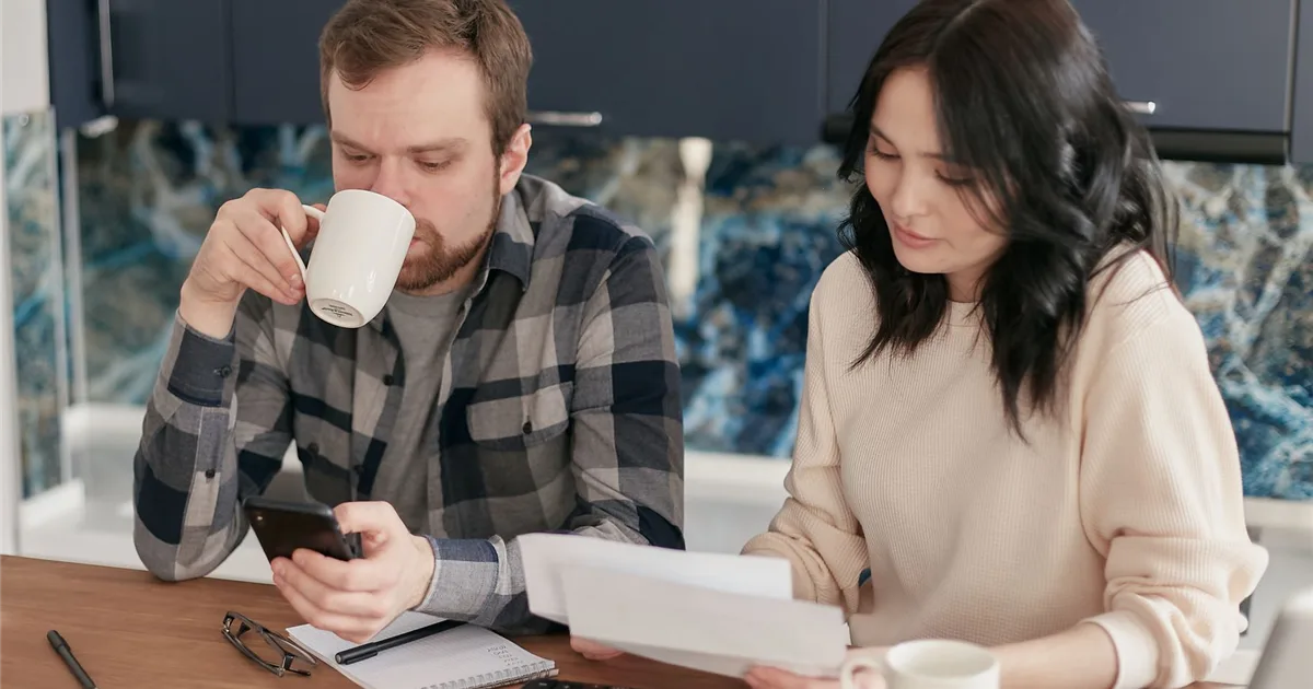 Couple checking whether a no refusal loans offer adds up with a calculator at the kitchen table